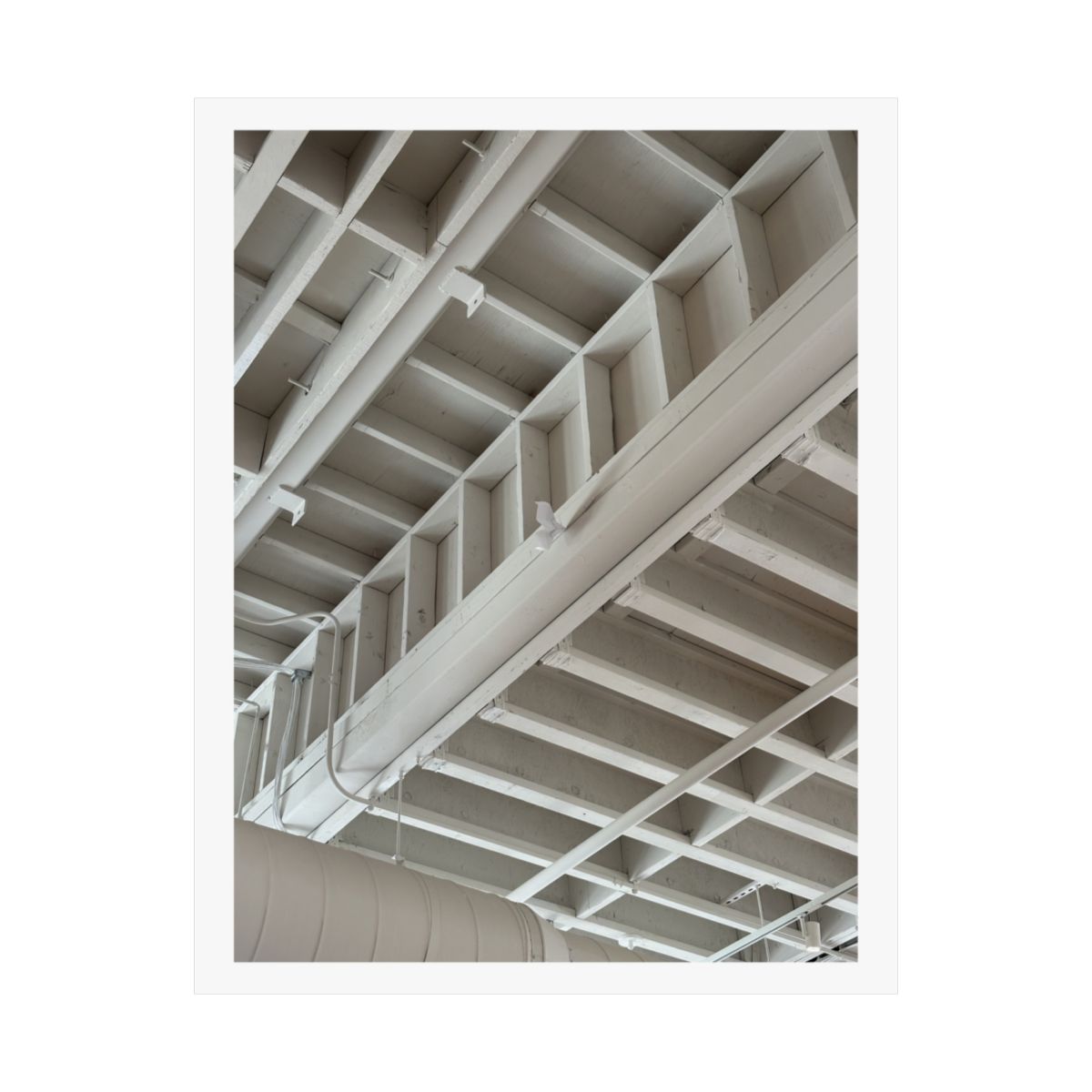 Print of a photograph looking up at white painted ceiling beams and pipework.