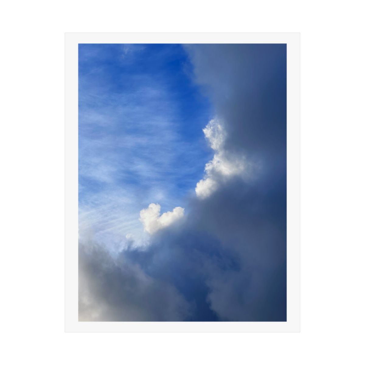 Print of a photograph of a tall white cloud rising through grey haze against dark blue sky.