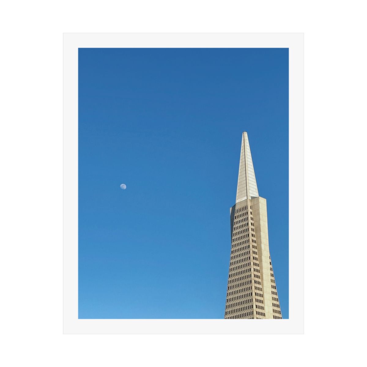 Print of a photograph of the Transamerica Pyramid against deep blue sky with a pale moon.