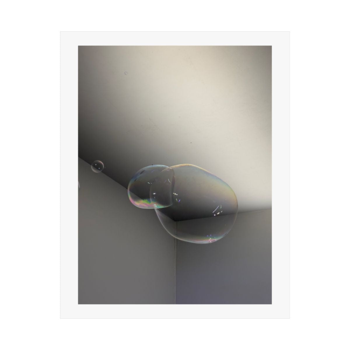 Print of a photograph of a single soap bubble in the corner of a pale empty room.