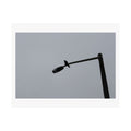 Print of a photograph of a black angled lamp arm against a plain grey ground.
